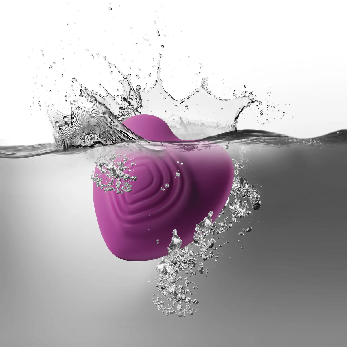Purple heart-shaped silicone massage toy partly submerged with splash droplets