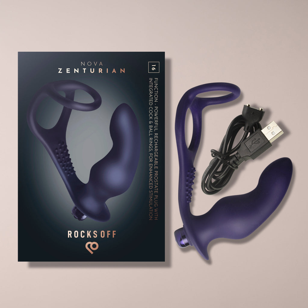 A photograph showing the product packaging and the contents of the Rocks Off NOVA Zenturian package laid out against a plain beige background. On the left is the dark gray retail box featuring an image of the device, the product name "NOVA Zenturian",