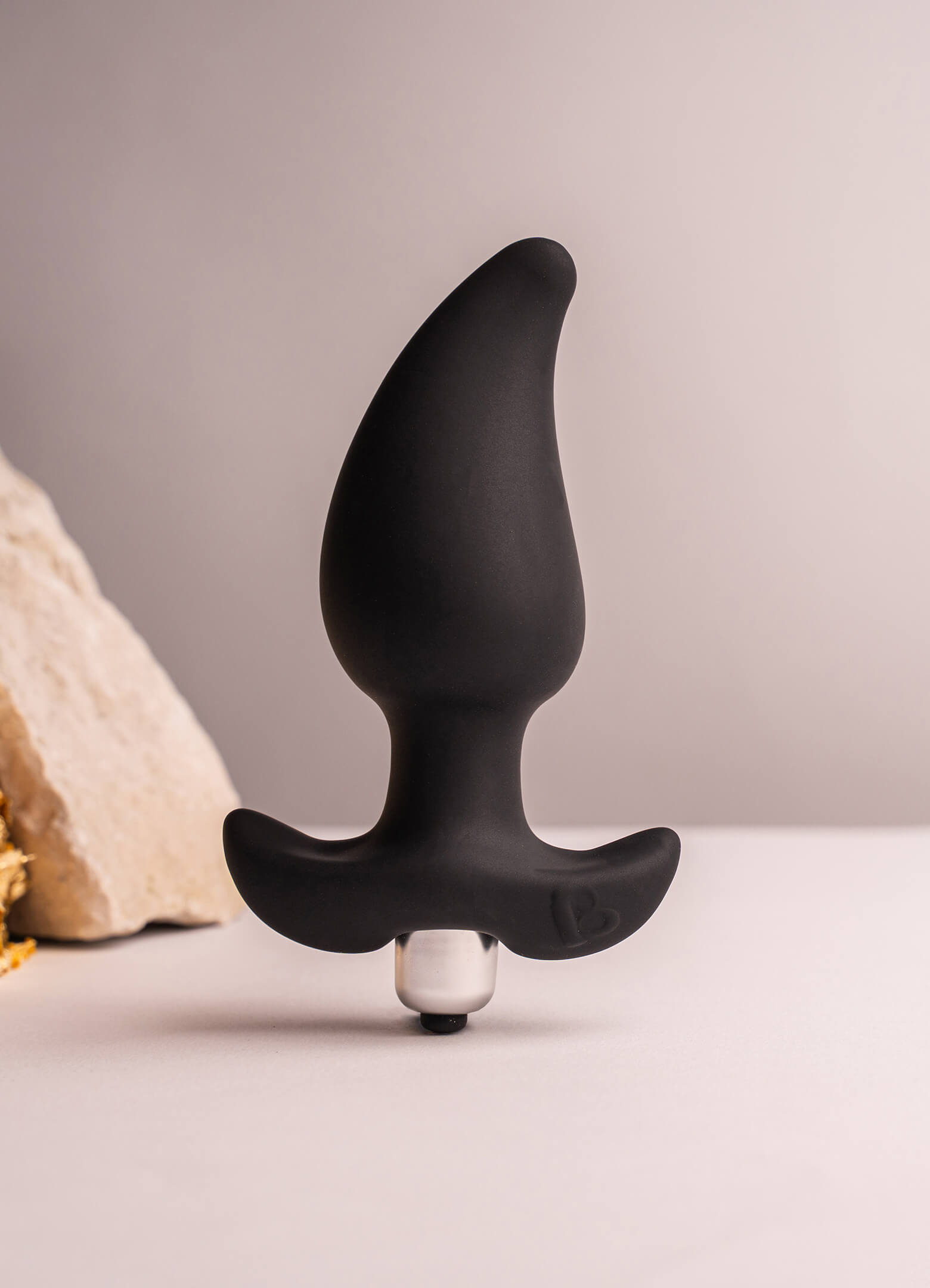Black pear shaped butt plug with a flared based housing a removable bullet vibrator.