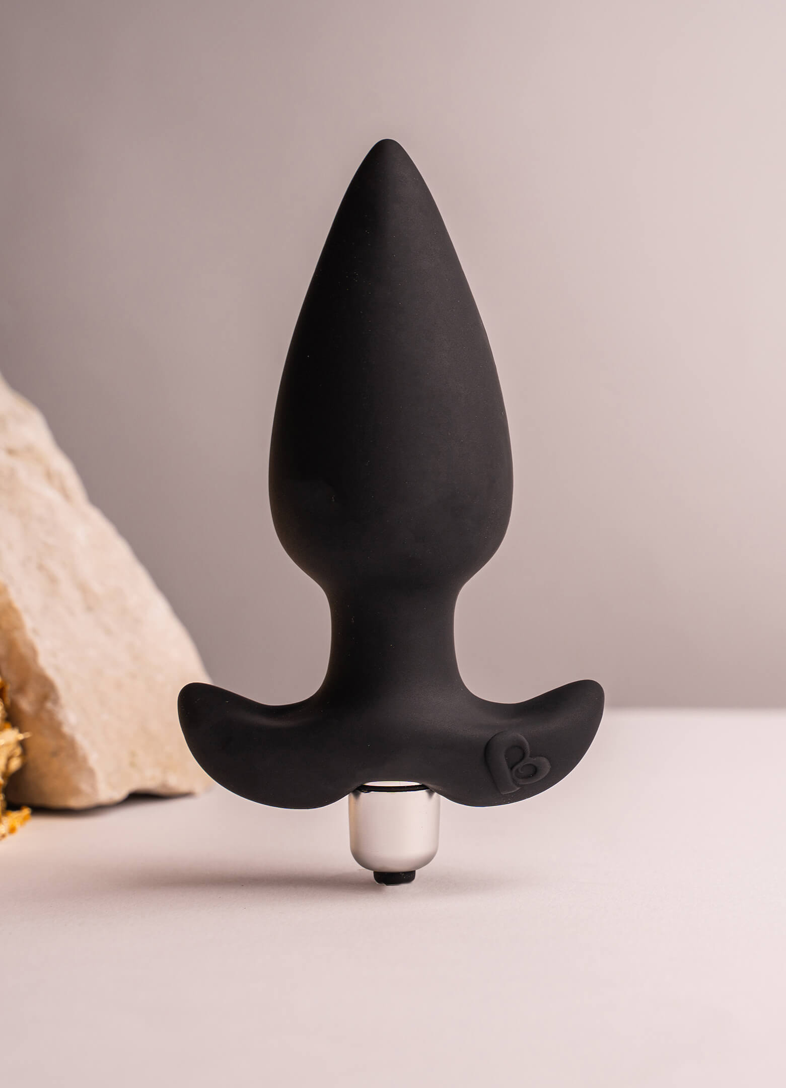 Black silicone tapered tip butt plug with a flared based housing a removable bullet vibrator.