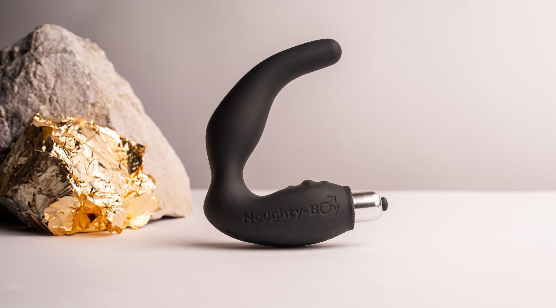Silicone prostate massager with rippled perineum pleasure points housing a removable bullet vibrator in black.