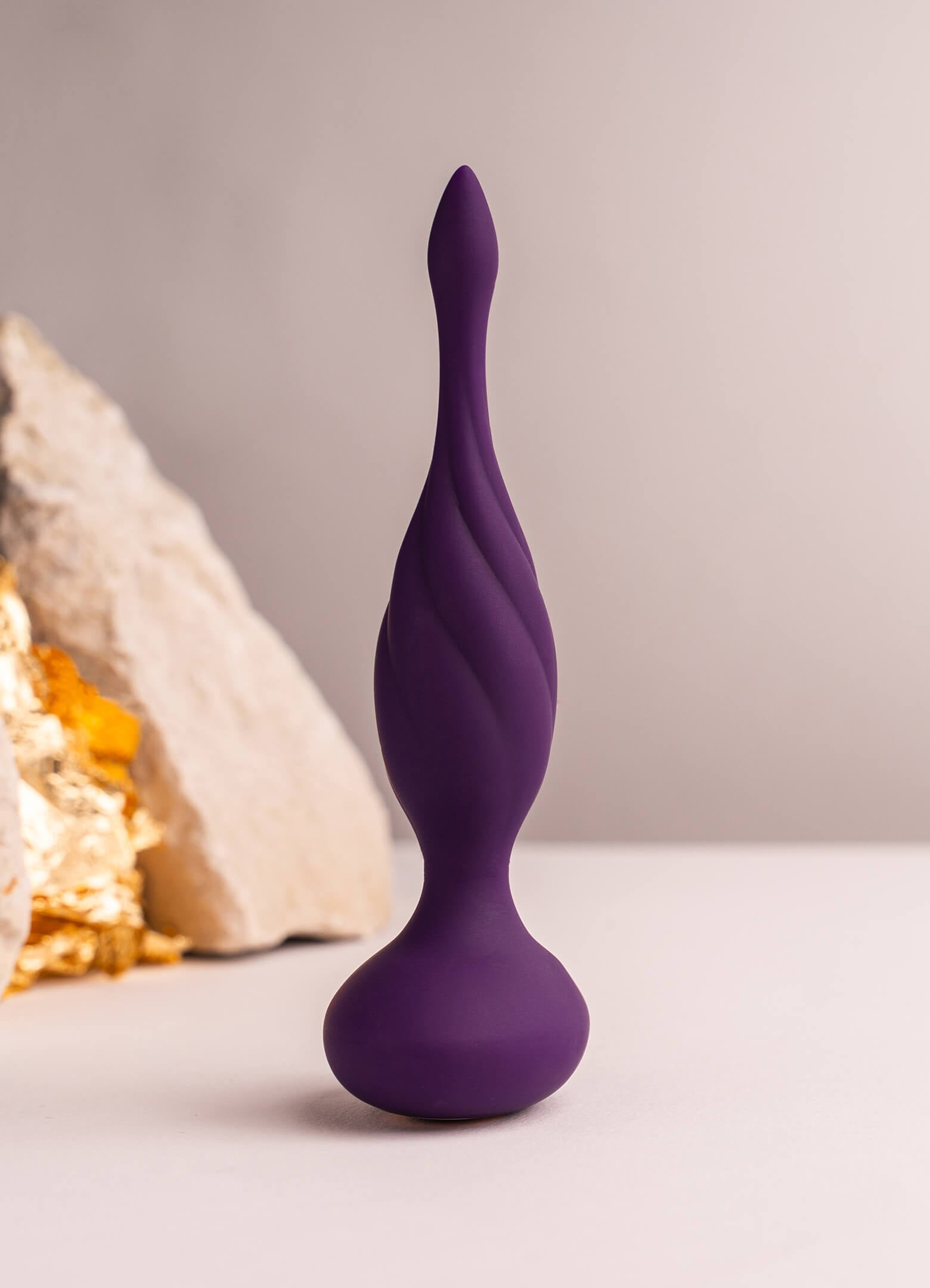 Thin tipped black silicone butt plug with a twisted surface design.