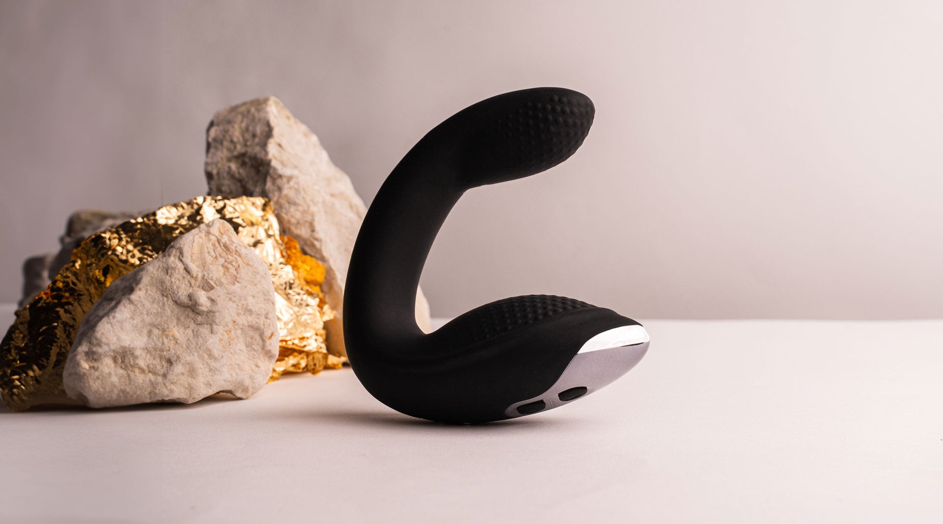 Vibrating C-shaped remote prostate massager with perineum stimulation base in black.