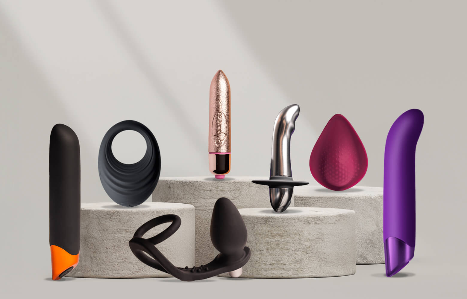 Collection of products on a stone podium including c-ring, panty vibe and g-spot vibrator