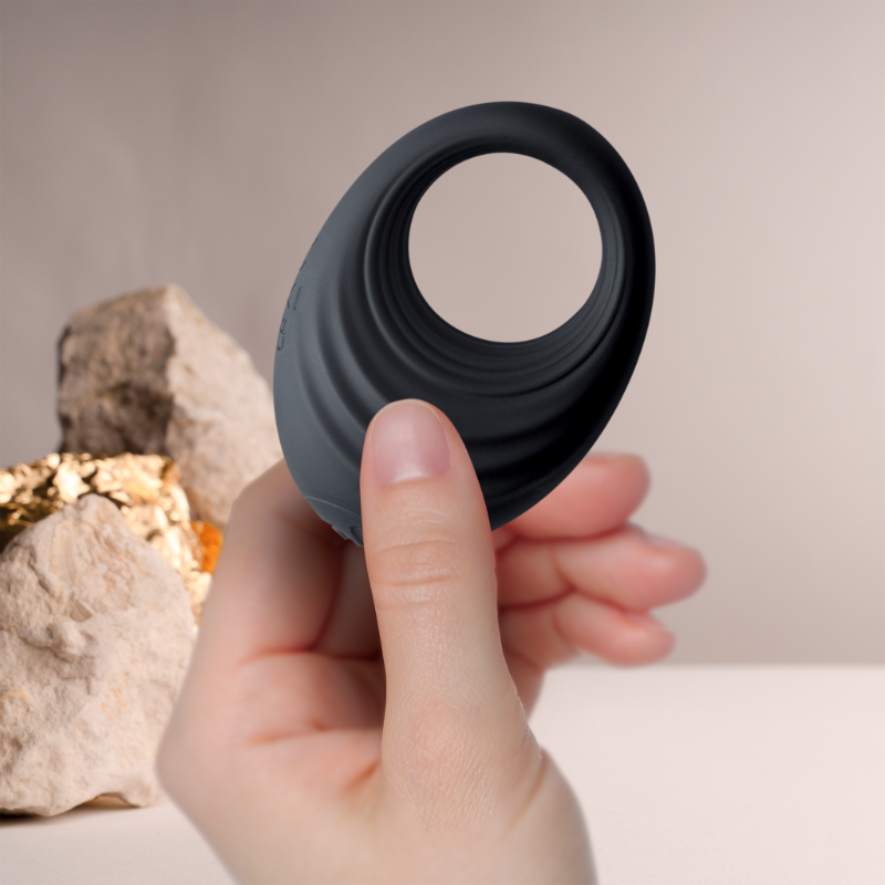 Black silicone cock ring held in fingers, open loop view