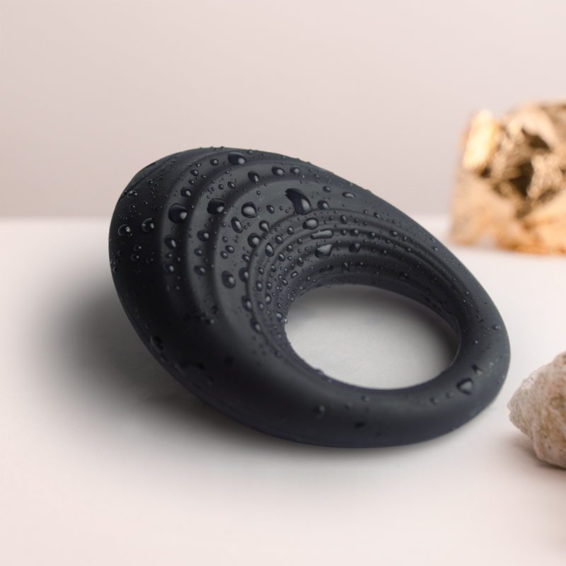 Black silicone cock ring with water droplets, close-up of outer surface