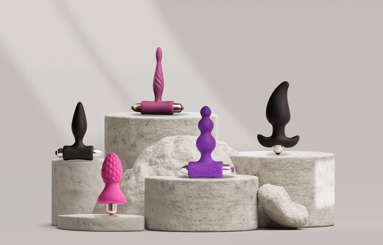 Collection of various sized butt plugs on a stone podium including various colours