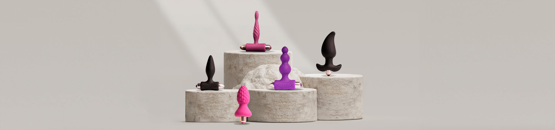 Collection of various vibrating butt plugs on a stone podium from different ranges