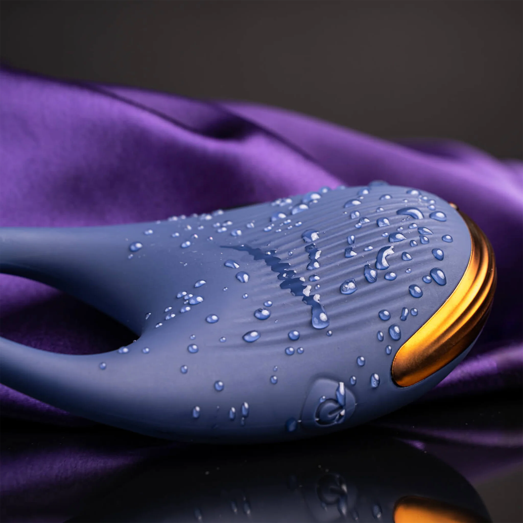 Navy blue ribbed silicone wearable device with raised nubs, gold edge, water droplets