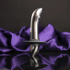 Metallic plug with flared tip and wide base, front view on purple fabric