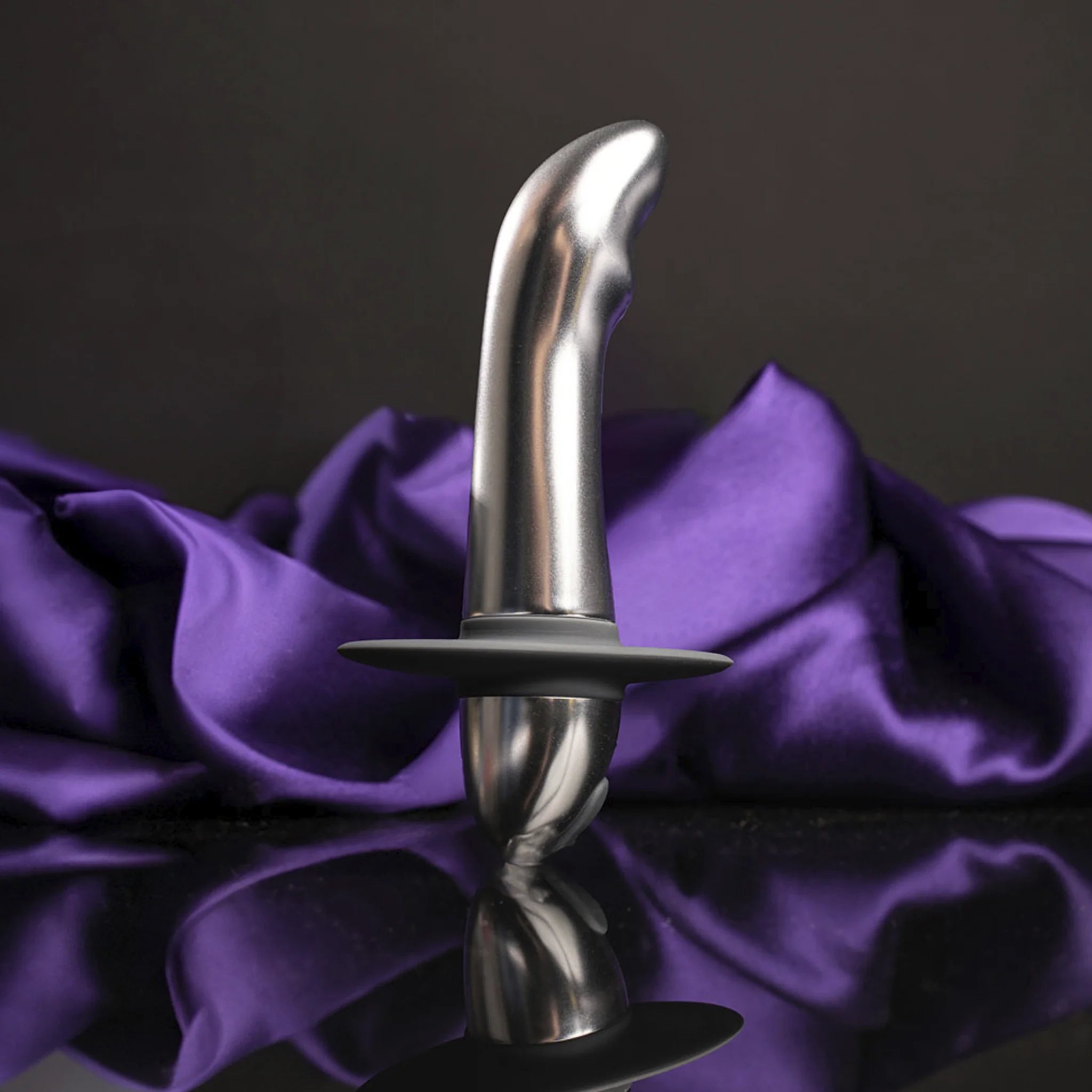 Metallic plug with flared tip and wide base, front view on purple fabric