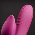 Bright pink rabbit-style massager with two curved textured silicone tips