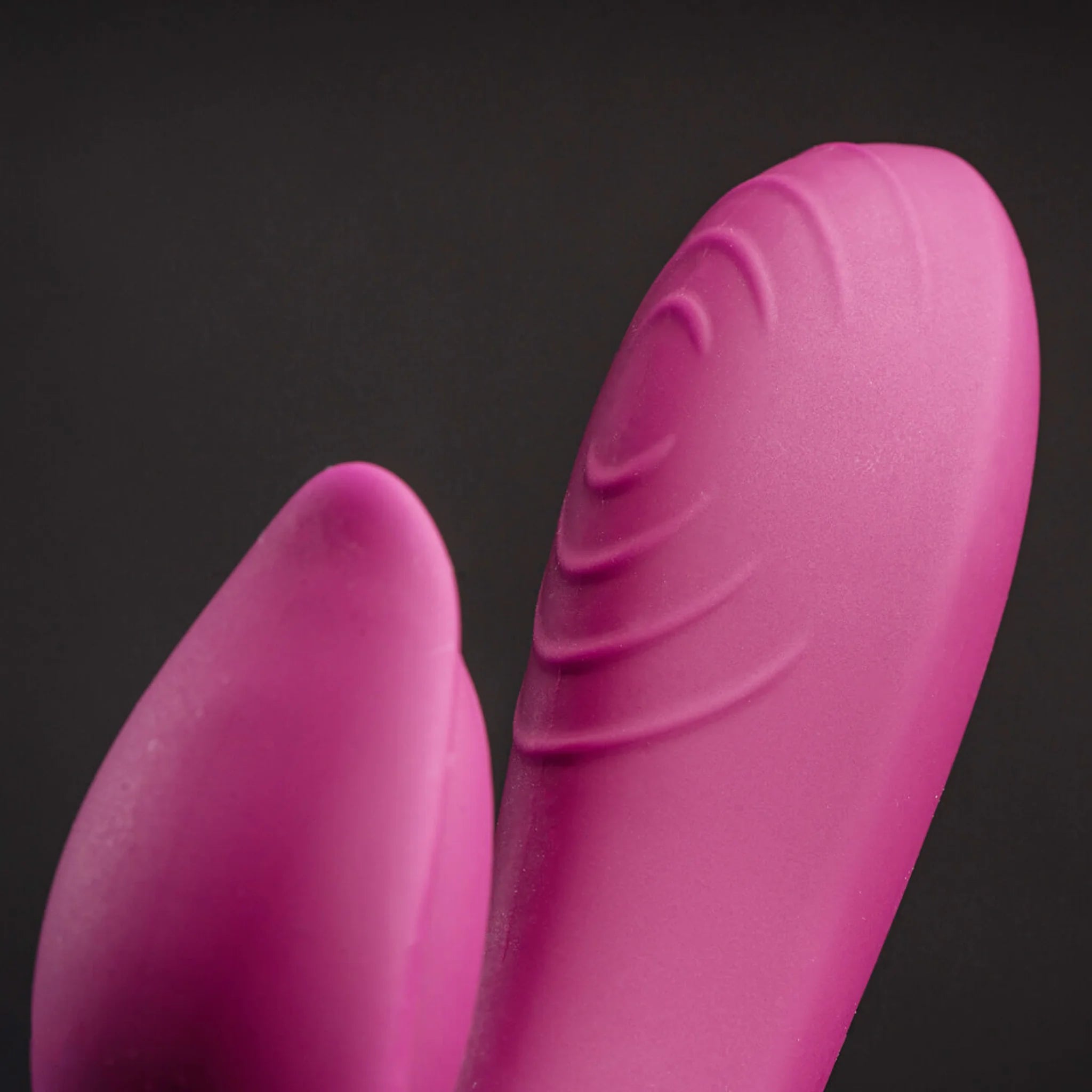 Bright pink rabbit-style massager with two curved textured silicone tips