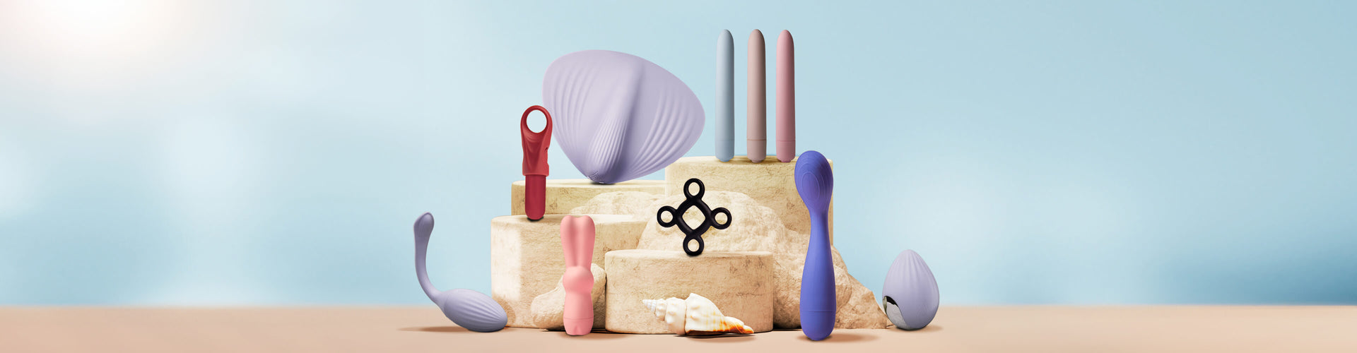 Collection of sex toys including bullets and vibrators on a sandy podium with seashells on a blue background