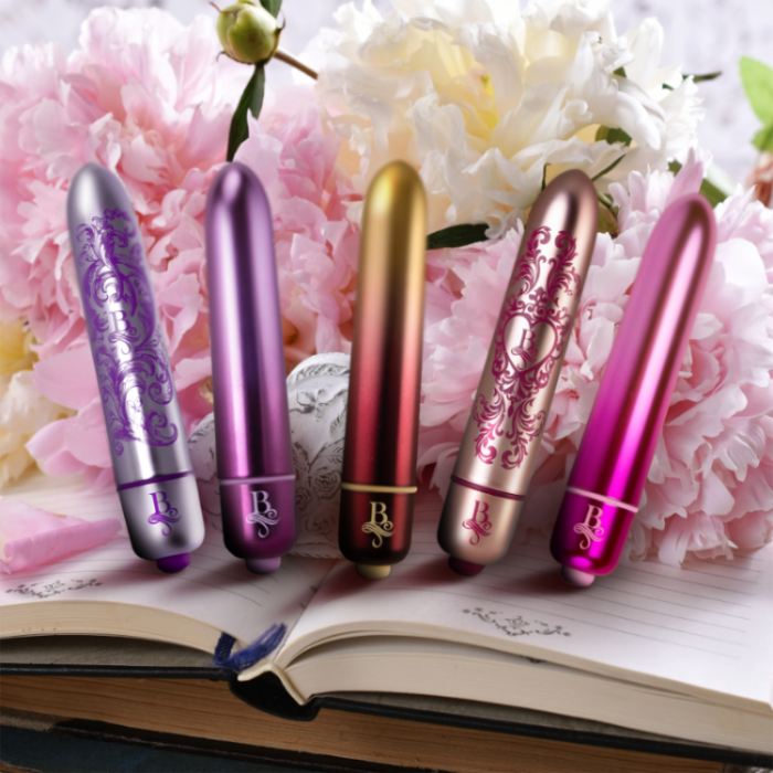 Set of decorative bullet vibrators in purple, gold, and magenta with ornate emblem details