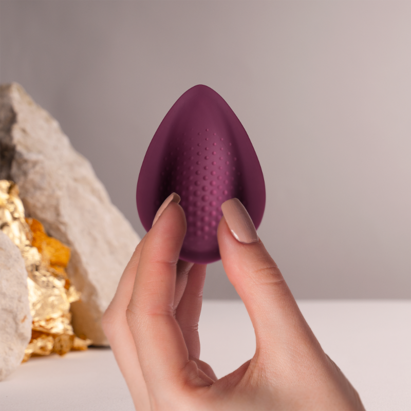 Maroon teardrop silicone massager held by two fingers