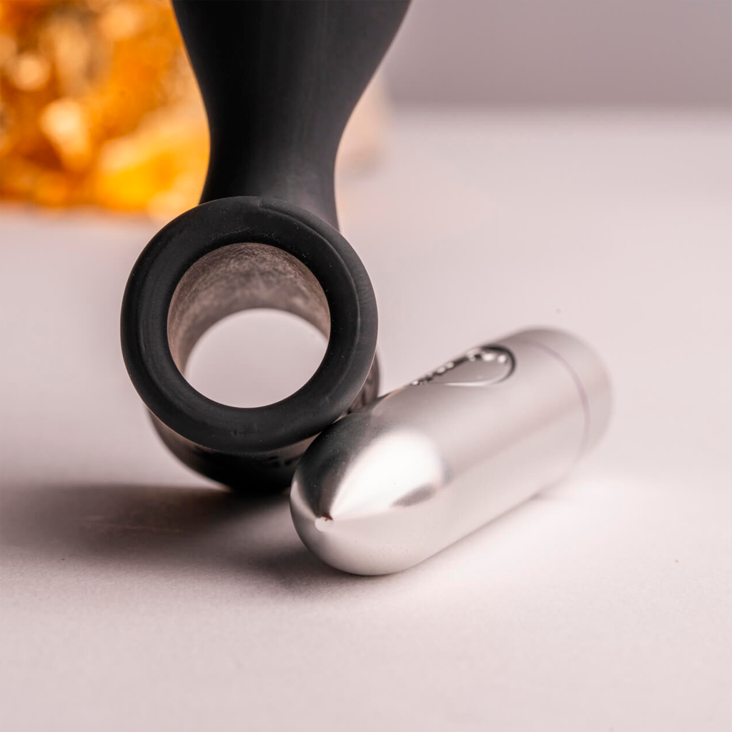 Black silicone anal plug with round base ring and silver vibrator attachment