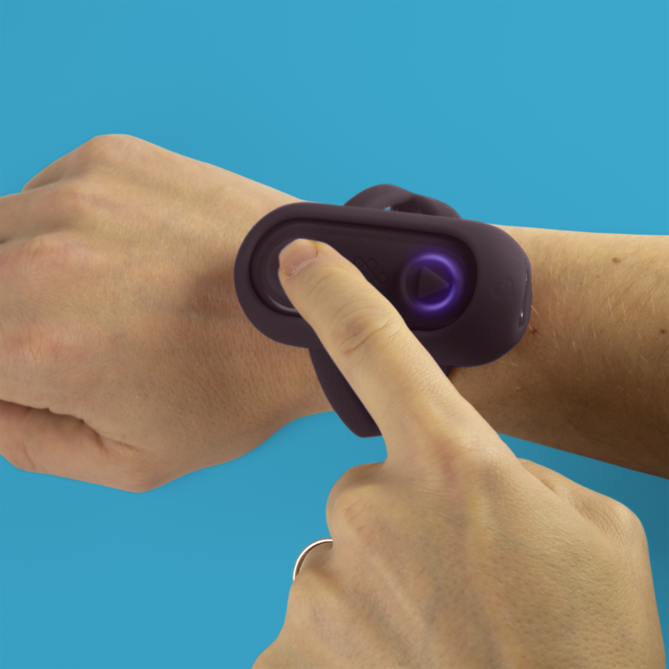 Purple silicone remote controller pressed against forearm with glowing button