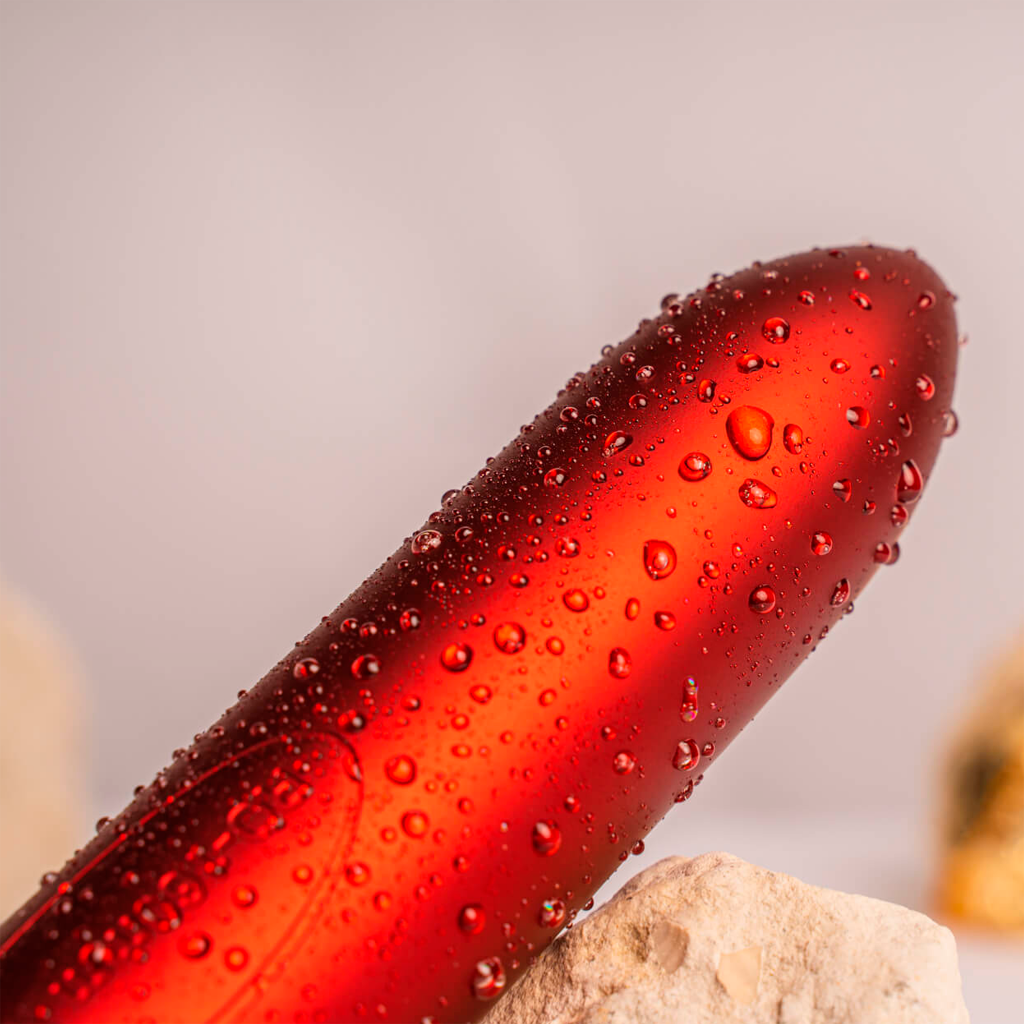 Red lipstick bullet covered with water droplets