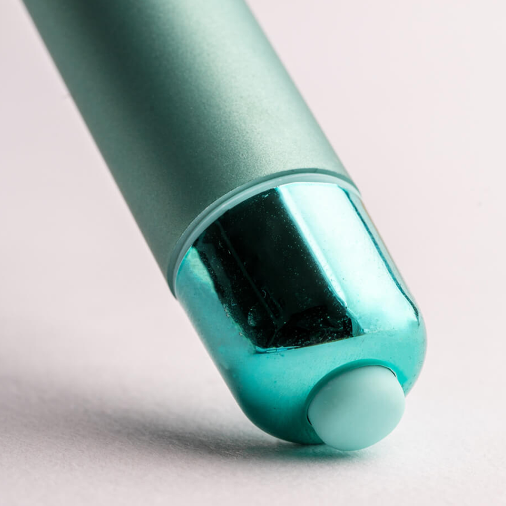 Teal bullet vibrator detail: rounded tip with dark internal window and light end cap