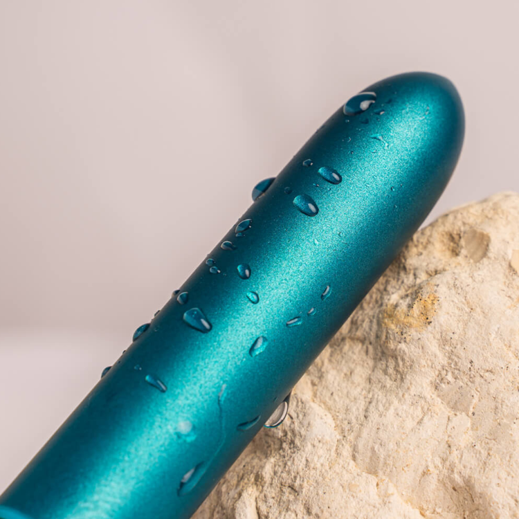 Teal bullet vibrator with water droplets on the body and sloped rounded tip