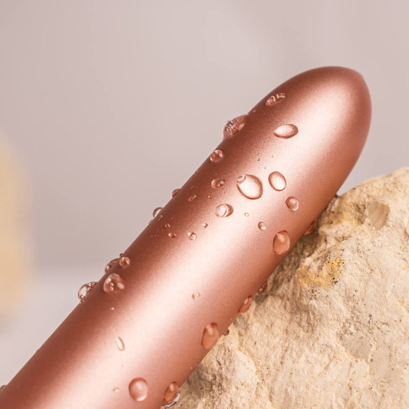 Rose gold bullet vibrator with water droplets on the body