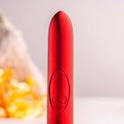 Scarlet Velvet bullet vibrator, product shown in close up on precision tip and embossed logo. Blurred rock in the Background for sense of scale.