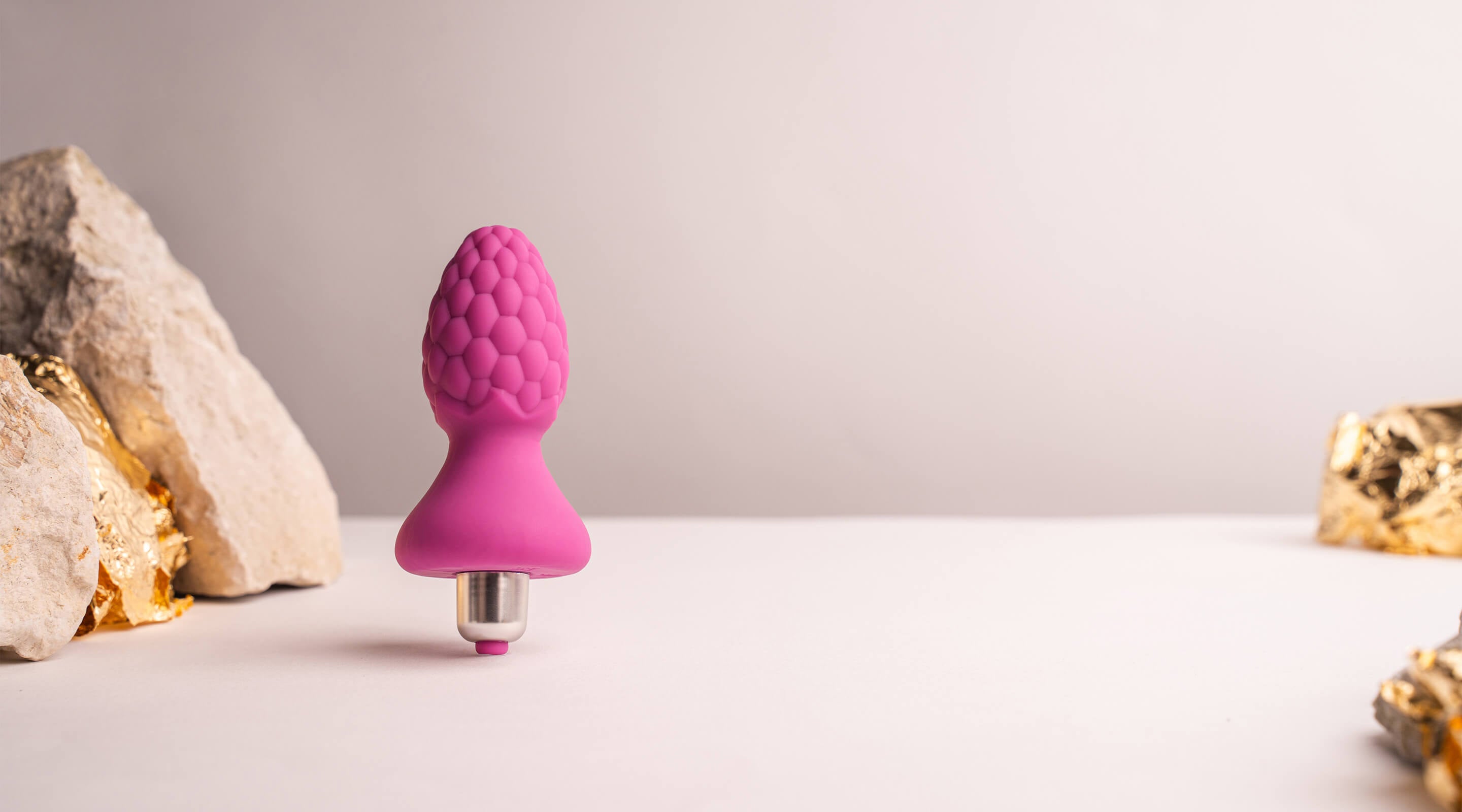 Pink butt plug with raspberry pattern texture housing a removeable bullet vibrator.