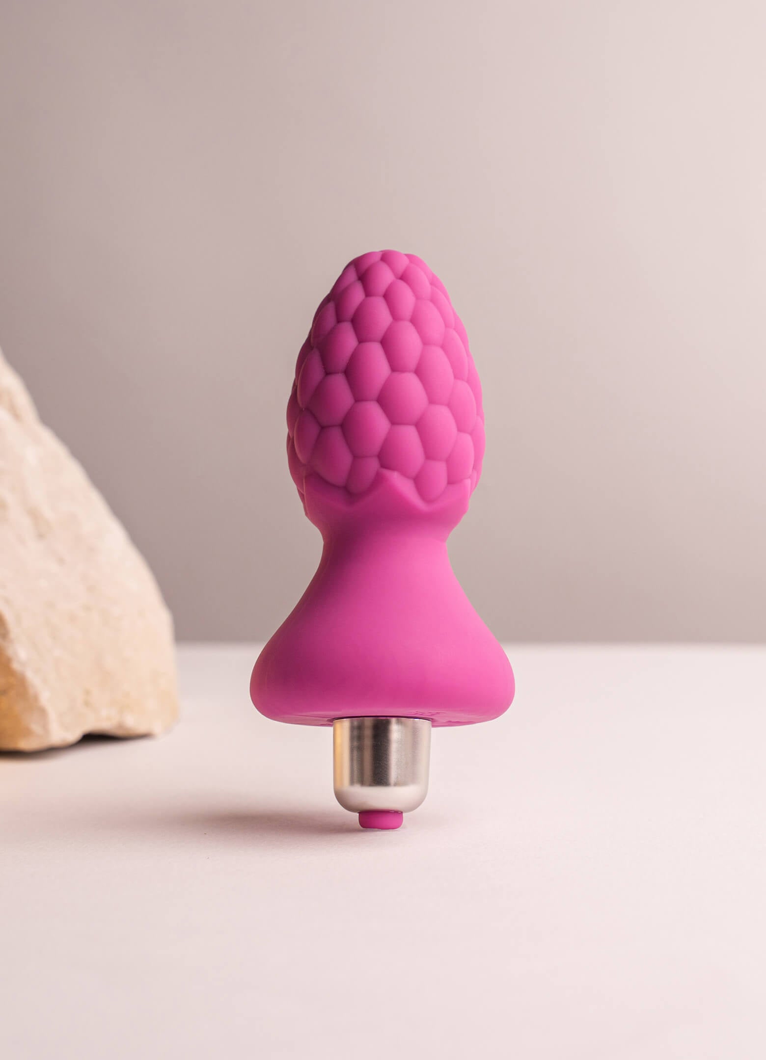 Pink butt plug with raspberry pattern texture housing a removeable bullet vibrator.