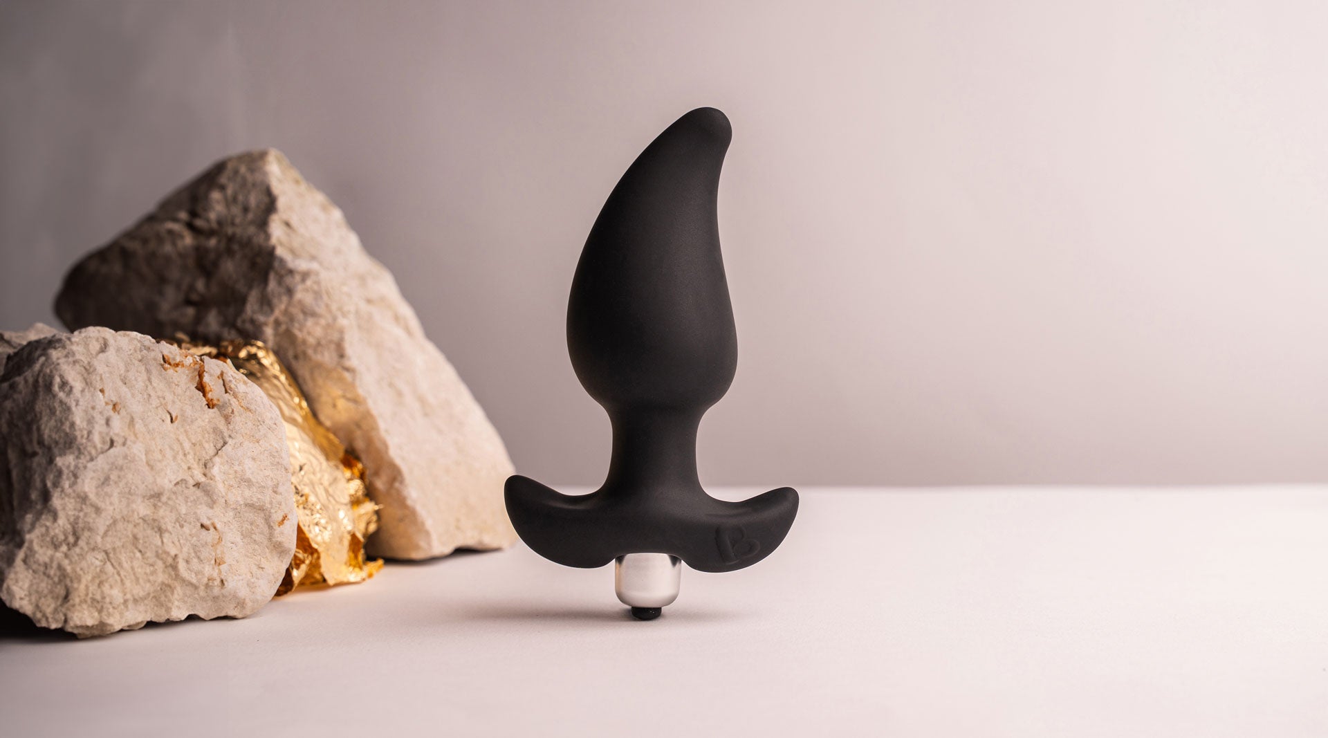 Black pear shaped butt plug with a flared based housing a removable bullet vibrator.