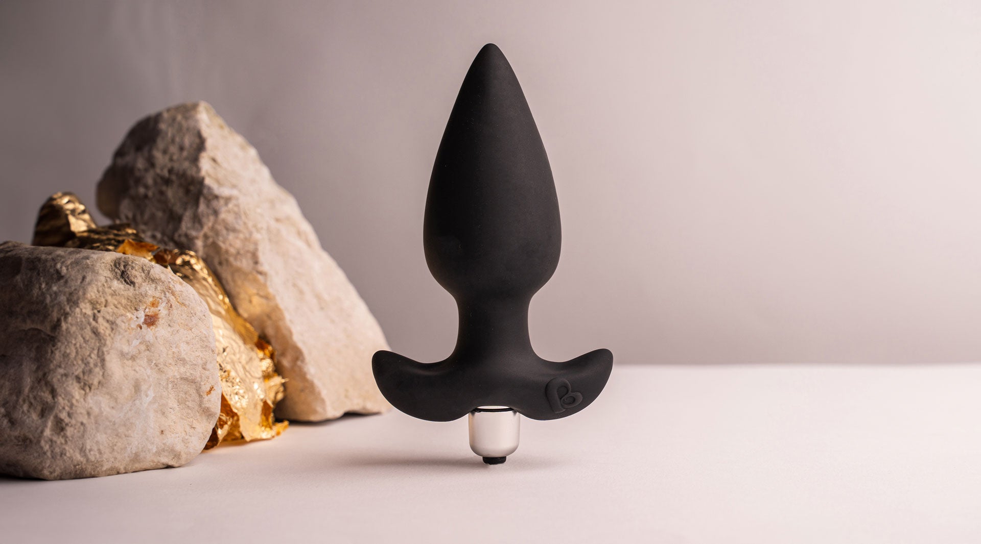 Black silicone tapered tip butt plug with a flared based housing a removable bullet vibrator.