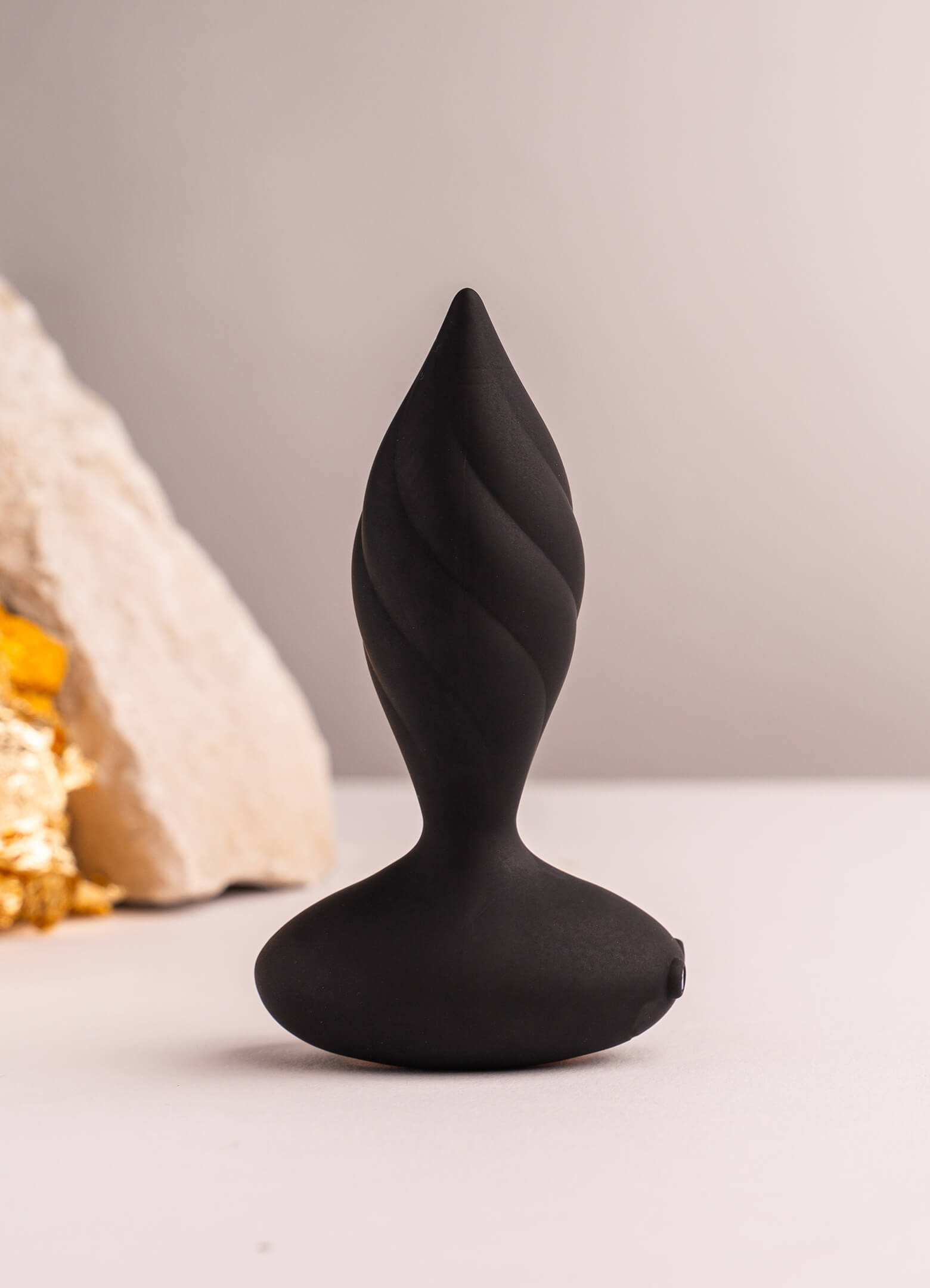 Black silicone butt plug with a tapered tip and twisted surface design.
