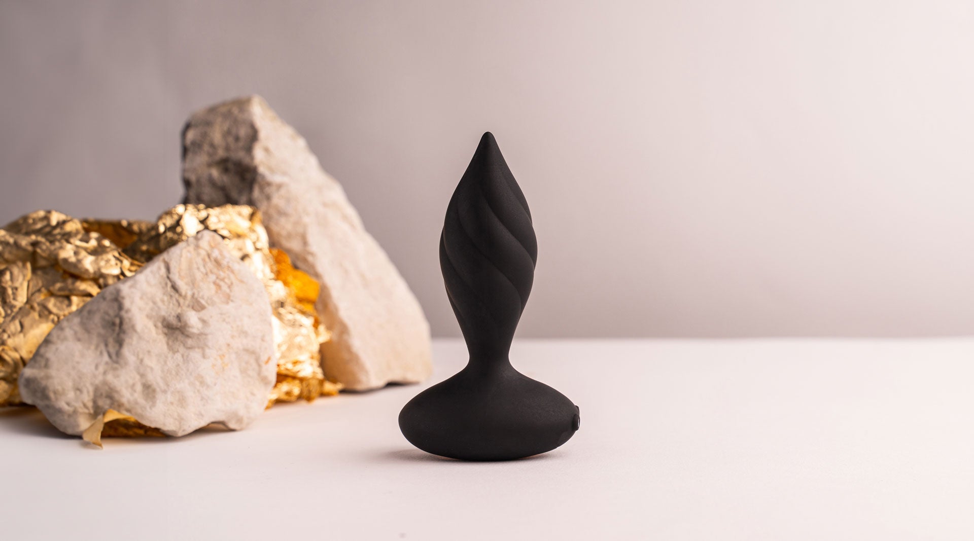 Black silicone butt plug with a tapered tip and twisted surface design.