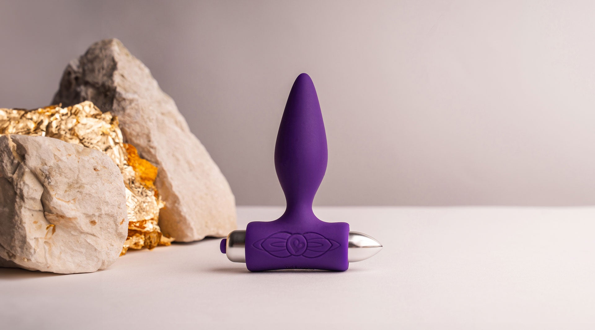 Purple silicone tapered tip butt plug housing a removable bullet vibrator.