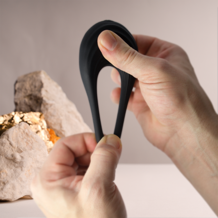 Black silicone cock ring stretched by hands, showing the inner opening
