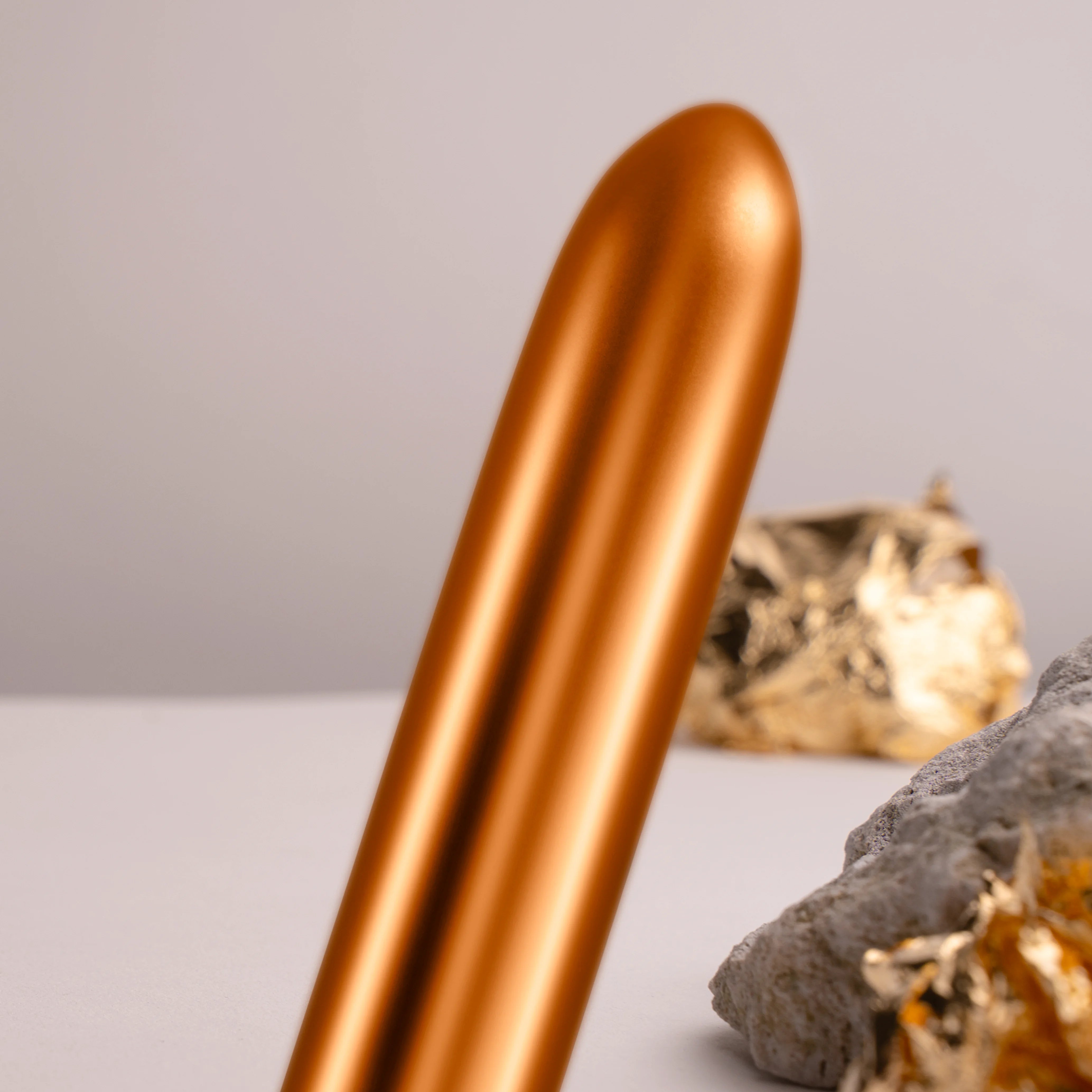 Havana orange metallic massager wand close-up, black control cap at base