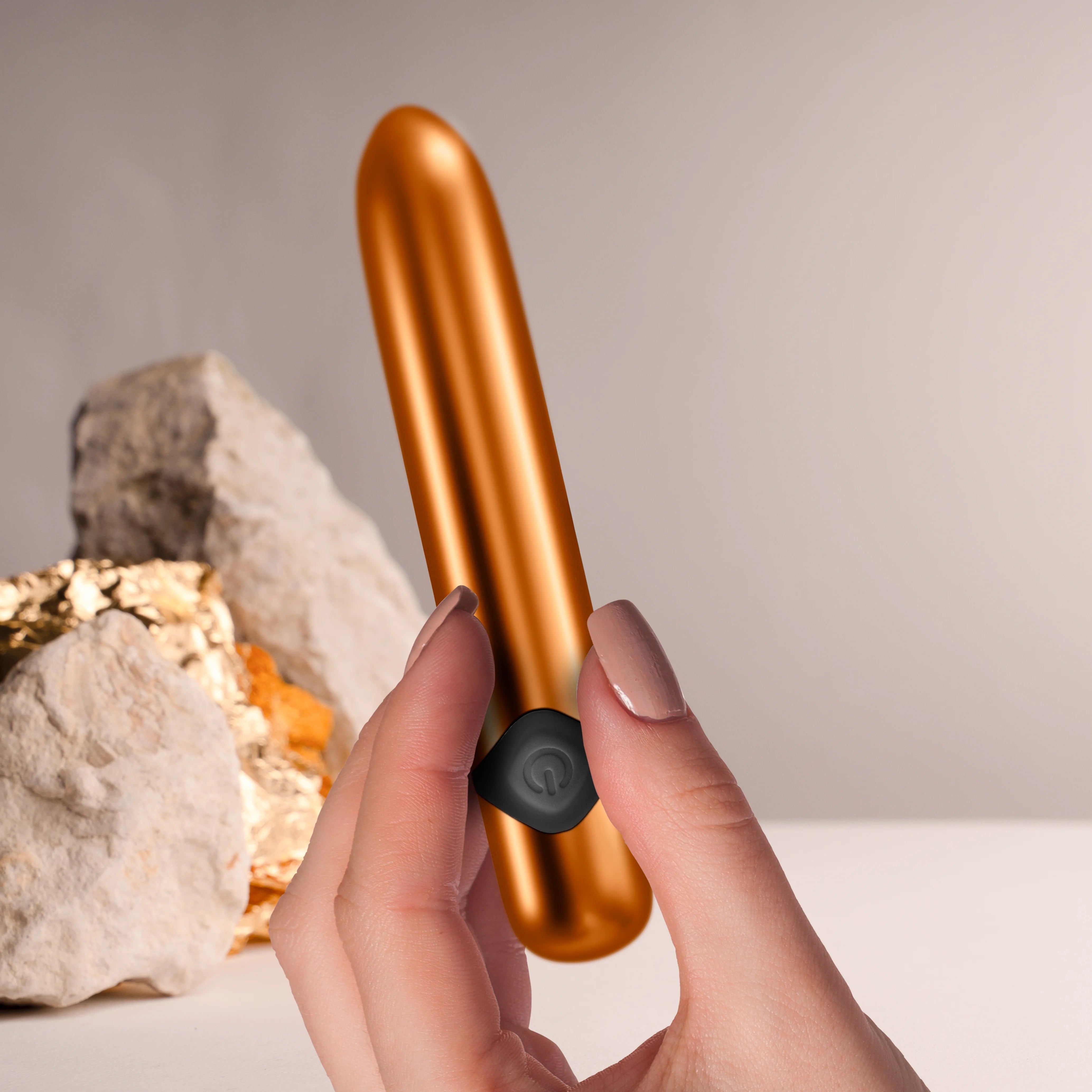 Havana orange metallic massager wand held in hands, black control cap visible