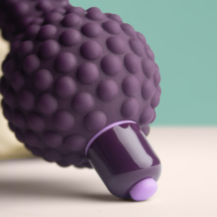 Purple silicone massager head close-up with bubble-like texture and base stem