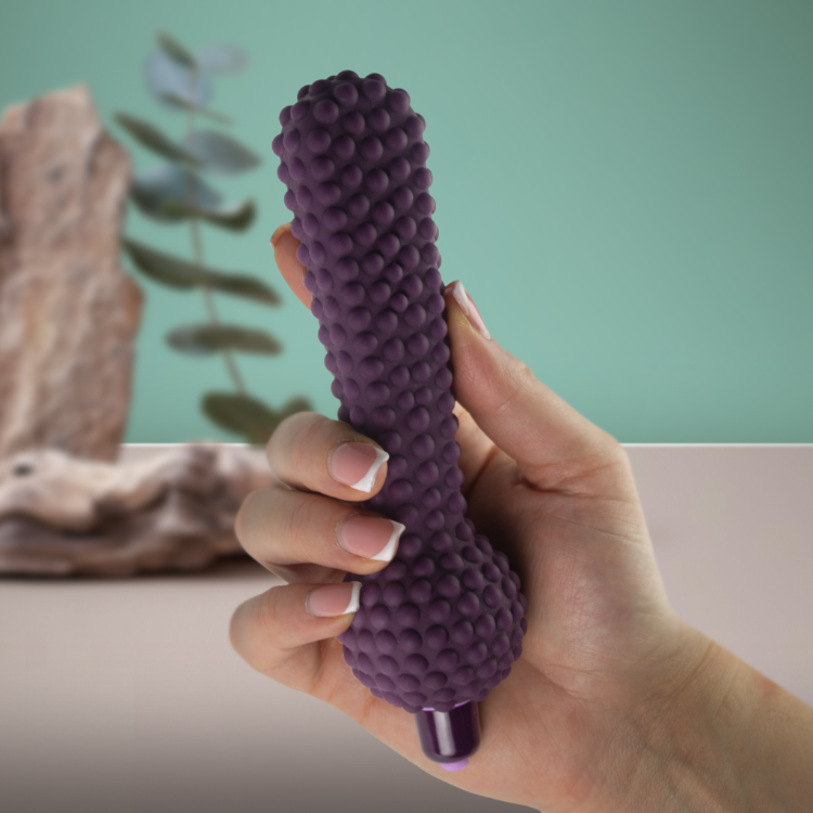Purple bumpy silicone massager held in hand with rounded bulb head and base tip