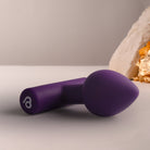 Purple butt plug on a light surface with a neutral background