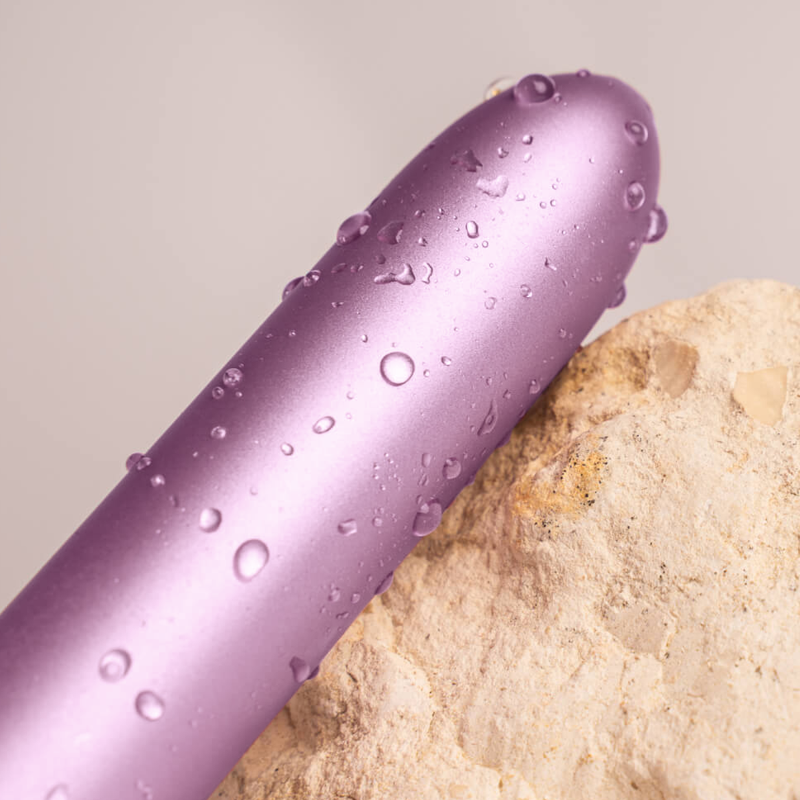 Purple bullet vibrator with water droplets across the smooth body